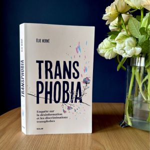 livre transphobia, posé sur une table, avec un vase à coté et des fleurs à l'intérieur.